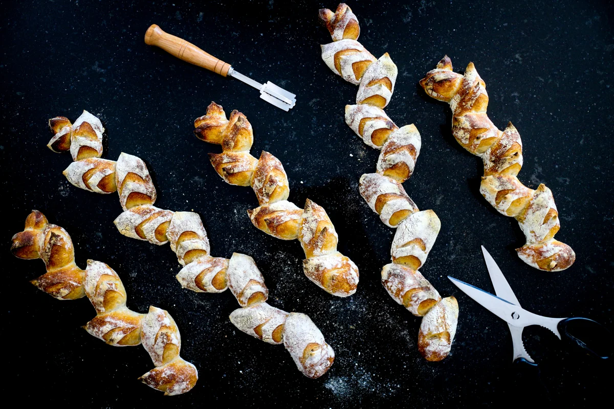 Baguettes maison façonnées en épis sur un plan de travail sombre.