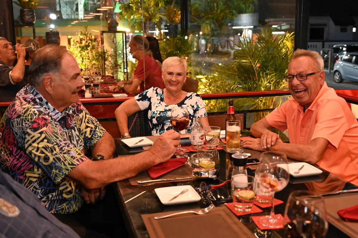 Trois personnes souriantes réunies autour d’une table au restaurant ; photo d’illustration.