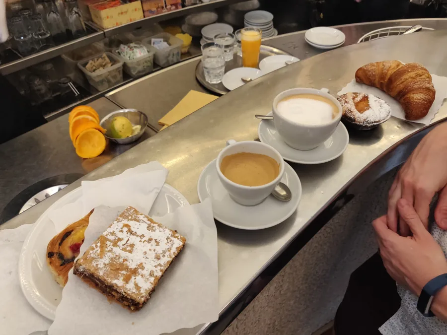 Deux cafés, un croissant et des pâtisseries sur un comptoir.