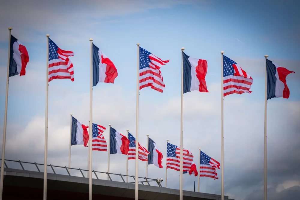 Les drapeaux français et américain flottent devant un ciel bleu à l’aéroport Paris-Orly.