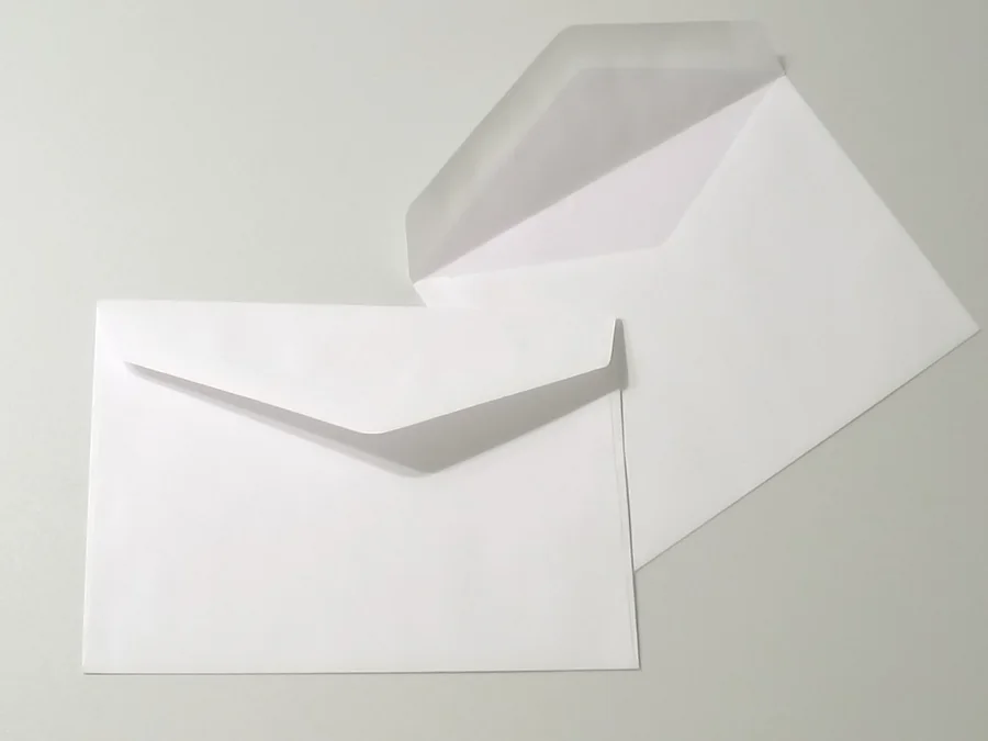 Deux enveloppes blanches, dont une ouverte, photographiées sur un fond clair.