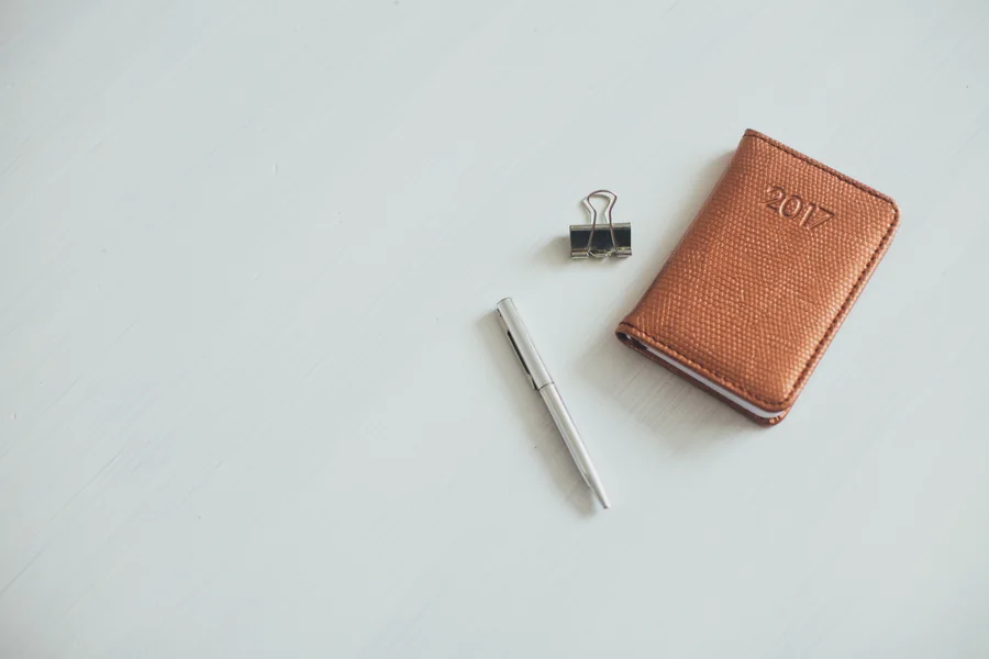 Un petit carnet en cuir marqué « 2017 », un stylo et une pince sur une table ; photo d’illustration.