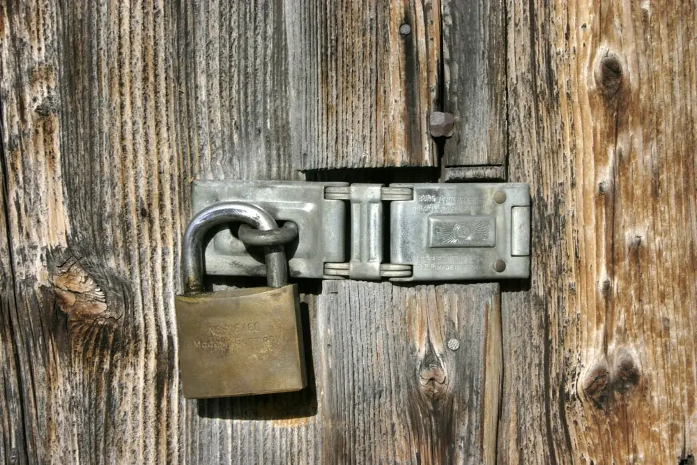 Un cadenas fermé sur le loquet d’une porte en bois, illustration de la protection.